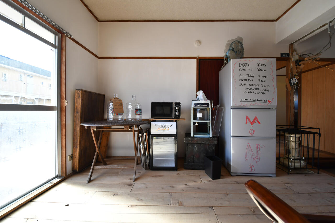 カフェスペースには電子レンジや冷蔵庫が置かれています。冷蔵庫の脇にアラジン社の灯油ストーブが置かれています。|1F リビング