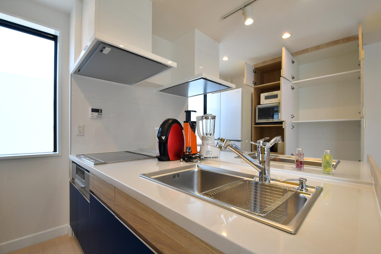 水栓はシャワーに切替可能です。収納棚は専有部ごとにスペースが用意されています。|1F キッチン