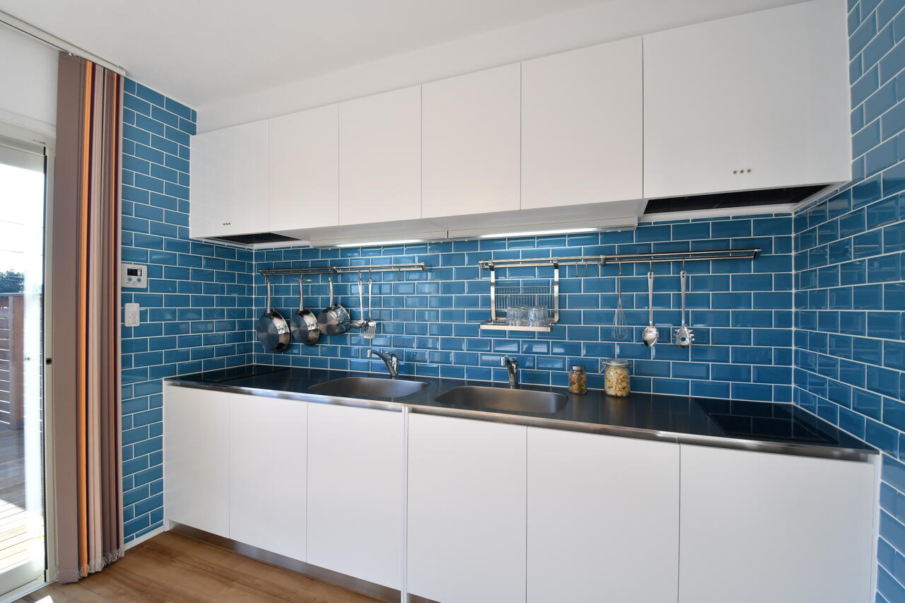 キッチンの様子。青いレンガはイタリア製とのこと。シンクとIHクッキングヒーターは2箇所ずつ設置されています。|1F キッチン