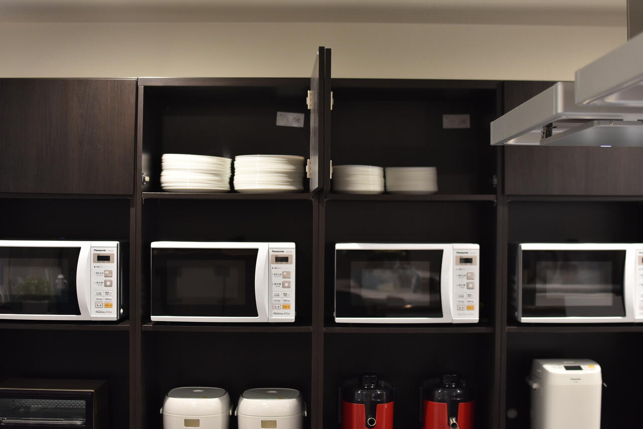 収納棚の上に共用の食器が用意されています。（A棟）|1F キッチン