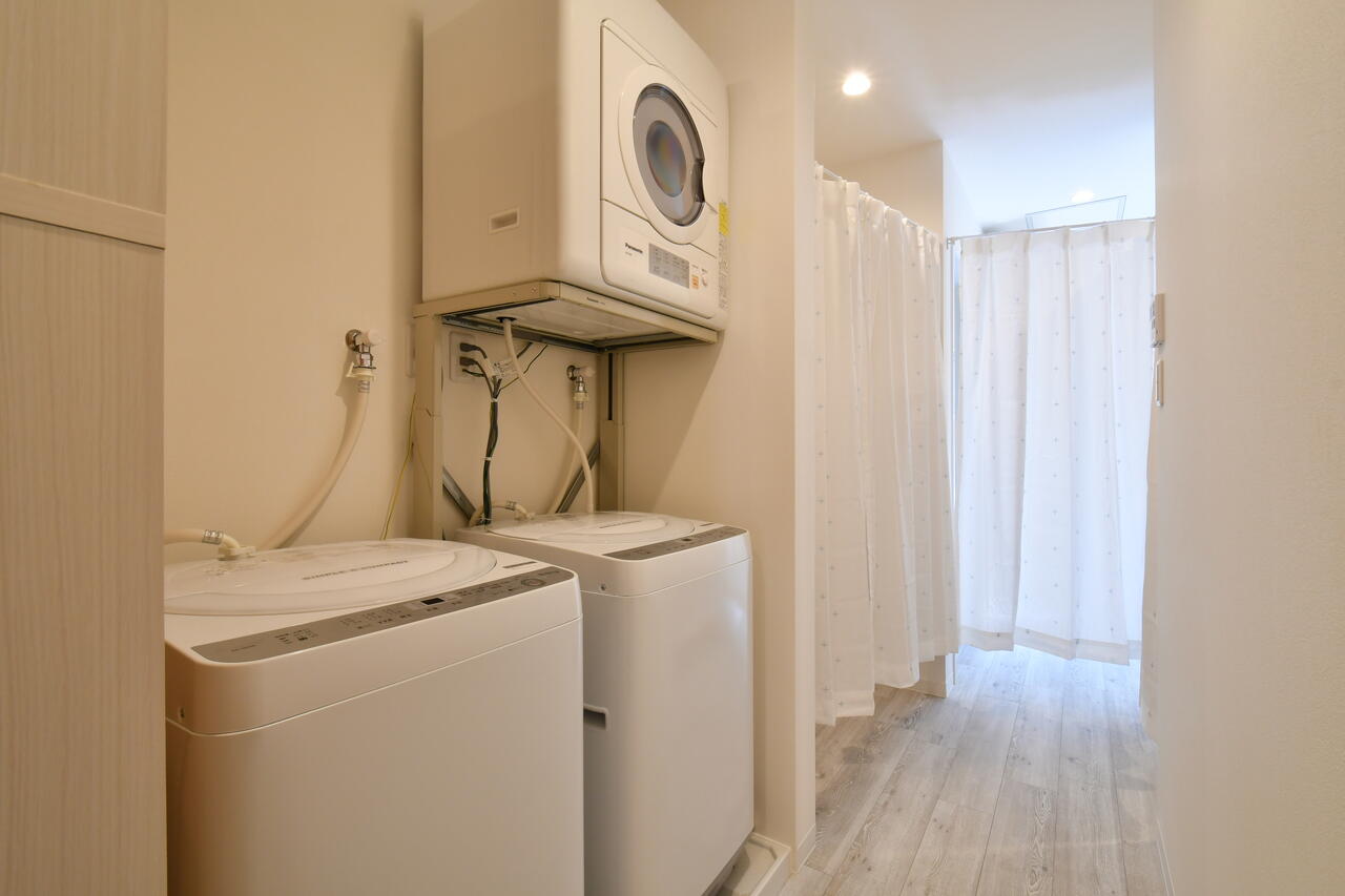 洗濯機と乾燥機の様子。突き当たりはシャワールームとバスルームです。|1F ランドリー