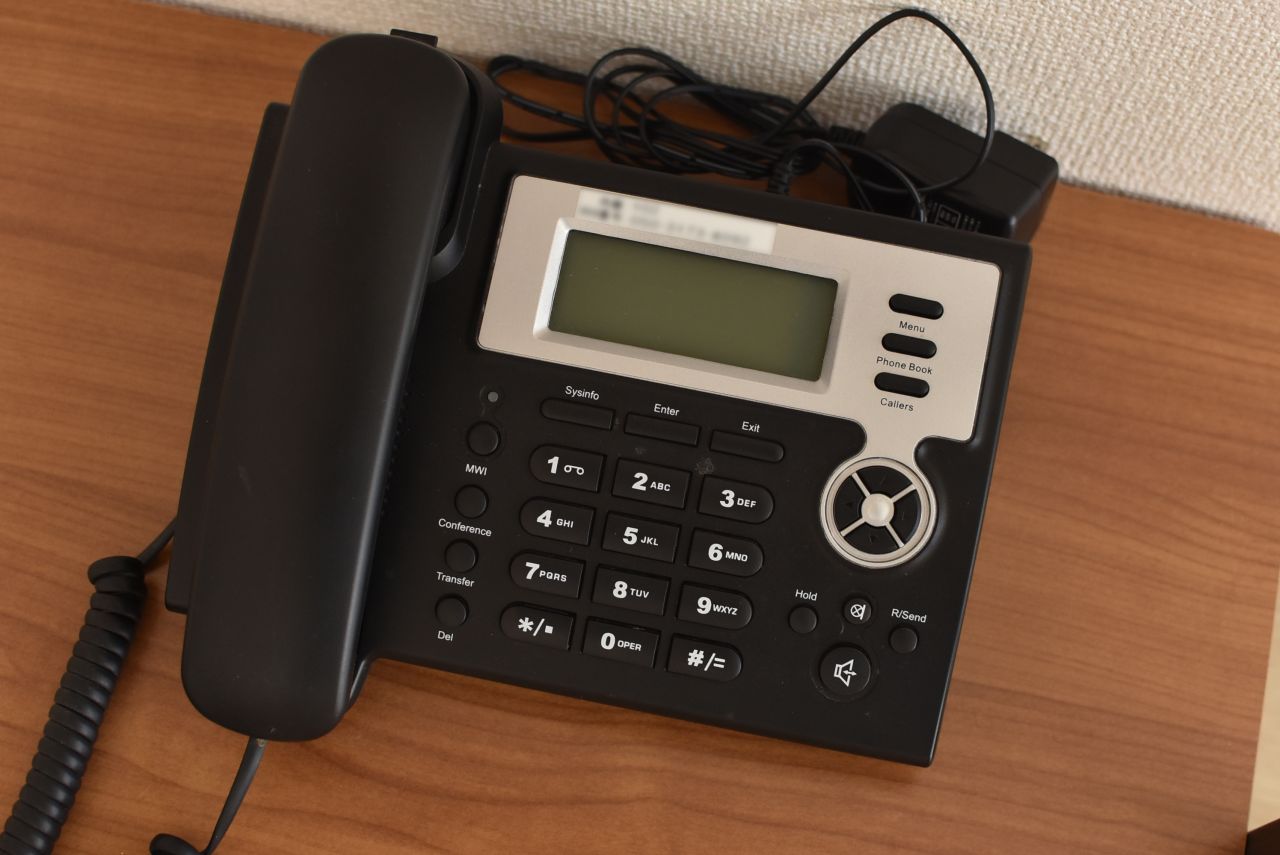 ハンガーラックには電話機が置かれています。電話機は有料でIP電話として使用することができるとのこと。（102号室）|1F 部屋