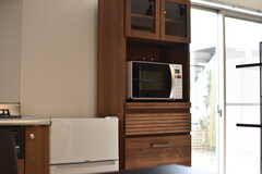 ガスコンロの脇に冷蔵庫と食器棚が設置されています。食器棚には電子レンジが用意されています。（101号室）(2018-04-06,専有部,ROOM,1F)