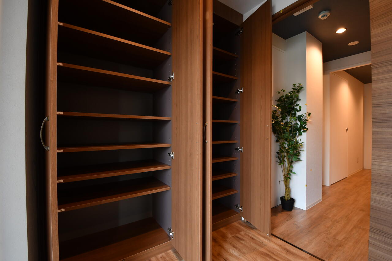 靴箱は専有部ごとにスペースが決められています。観葉植物の脇が階段です。|1F 玄関