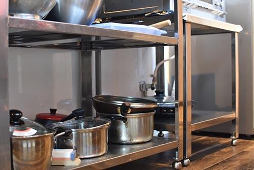 ガスコンロの下は共用の鍋やフライパンが置かれています。|1F キッチン