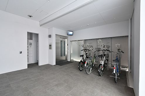 奥のエレベーター前に4台のシェア自転車があります。|1F 玄関