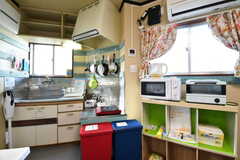 キッチンの脇に収納棚が設置されています。収納棚の上に電子レンジとオーブントースターが置かれています。収納棚の対面に洗濯機と洗面台が設置されています。(2020-02-03,共用部,KITCHEN,1F)