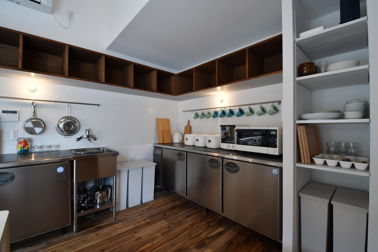 冷蔵庫の脇が食器棚です。冷蔵庫の上は専有部ごとに収納が用意されています。|2F キッチン