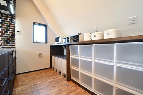 キッチンの対面は収納棚です。収納棚にキッチン家電が並んでいます。収納棚の下は専有部ごとにスペースが決められています。|3F キッチン
